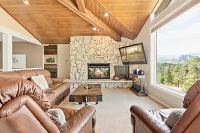 a living room with couches and a stone fireplace at Wanderlust Luxury Vacation Home at Windcliff condo in Estes Park