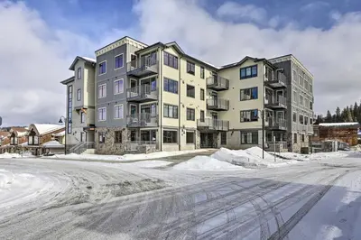 an apartment building in the snow on a street at Newly Built Ski Condo with Hot Tub and Shuttle Access! in Winter Park