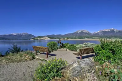 two benches sitting next to a lake with mountains in the background at Mtn Views and Hot Tub Access Lake Dillon Retreat in Dillon