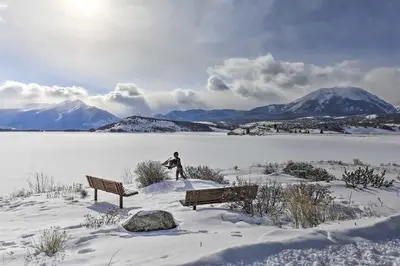 a statue of a man standing next to two benches in the snow at Mtn Views and Hot Tub Access Lake Dillon Retreat in Dillon