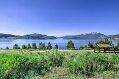 a bench next to a lake with mountains in the background at Mtn Views and Hot Tub Access Lake Dillon Retreat in Dillon