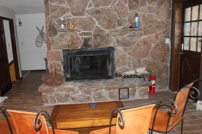 a stone fireplace in a living room with a table and chairs at Casa Colo in Fraser