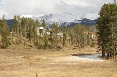 a house in the middle of a field with mountains at Casa Colo in Fraser