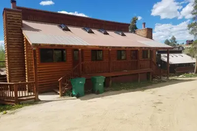 a wooden cabin with two green trash cans in front of it at Casa Vista Granby in Granby