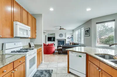 a kitchen with white appliances and a living room at Fenced Yard and Trail Access Dog-Friendly Erie Home in Erie