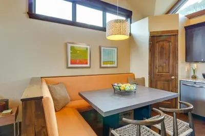 a dining room with an orange couch and a table at Frisco Condo with Rooftop Deck Walk to Main St! in Frisco