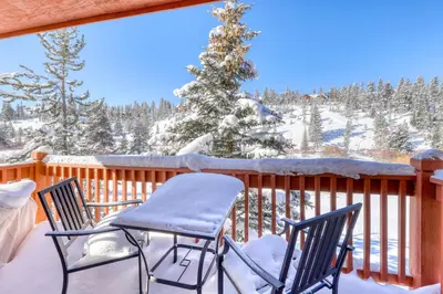 a balcony with two chairs and a snow covered tree at Revett Retreat in Breckenridge