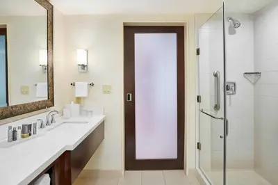 a bathroom with two sinks and a shower with a glass door at Denver Marriott Westminster in Westminster