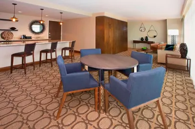 a living room with a table and blue chairs at Denver Marriott Westminster in Westminster