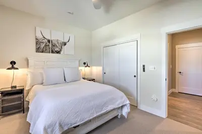 a bedroom with a white bed with a cow painting on the wall at Condo with View - 1 Block to Main St - 4 Mi to Ski! in Winter Park