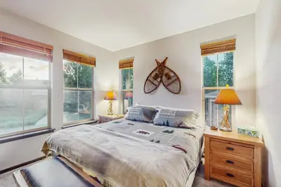 a bedroom with a bed and two lamps and windows at Tall Timber Getaway in Granby