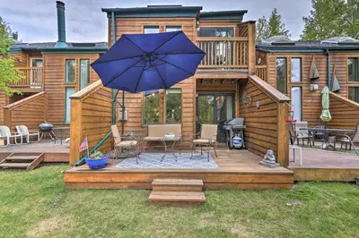 a wooden deck with a table and an umbrella at 7 Mi to Ski Waterfront Townhome in Frisco! in Frisco