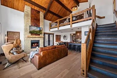 a living room with a staircase and a couch and a fireplace at The Bear's Getaway - Jacuzzi, Indoor/Outdoor Fireplace, Fantastic Location! in Estes Park