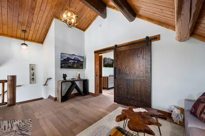 a living room with a wooden door and a table at Relax in The Rockies – Located on Lake Estes, Jacuzzi and Indoor/Outdoor Fireplace in Estes Park