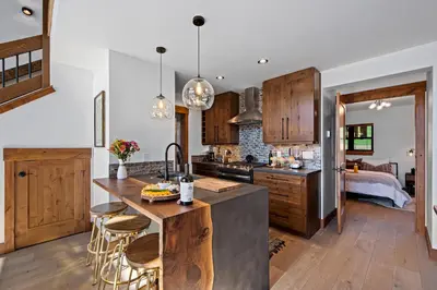 a kitchen with wooden cabinets and a kitchen island with bar stools at Cozy & Relaxing – Indoor/Outdoor Fireplace, Jacuzzi and BBQ grill in Estes Park