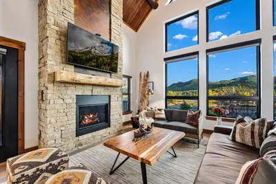 a living room with a fireplace and a stone wall at New Log cabin, The Bears Den - 2 bedrooms, loft, 2.5 bath, jacuzzi & Fireplace in Estes Park