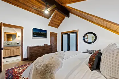 a bedroom with a large white bed and a bathroom at New Log cabin, The Bears Den - 2 bedrooms, loft, 2.5 bath, jacuzzi & Fireplace in Estes Park
