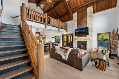 a living room with a staircase and a couch and a fireplace at New Log cabin, The Bears Den - 2 bedrooms, loft, 2.5 bath, jacuzzi & Fireplace in Estes Park