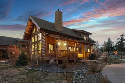 a log cabin with a deck and a sunset at New Log cabin, The Bears Den - 2 bedrooms, loft, 2.5 bath, jacuzzi & Fireplace in Estes Park