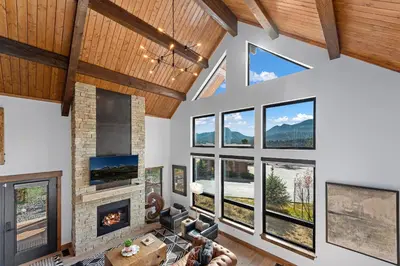 a living room with a fireplace and large windows at End Unit - EV Charger, Fireplace & Jacuzzi in Estes Park