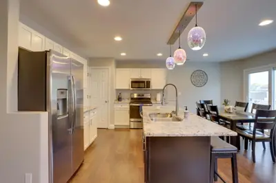 a kitchen with a refrigerator and a table with chairs at Denver Getaway Close to Downtown, Mtns, and Boulder in Thornton