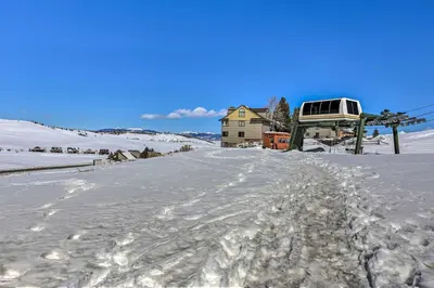 a snow covered road with a house and a ski lift at Ski-InandOut Granby Home with Gas Grill and Fire Pit! in Granby