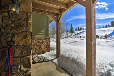 a house with a stone wall with a ski pole in the snow at Couples Ski Condo 1 Mi to Breckenridge Golf Club in Breckenridge