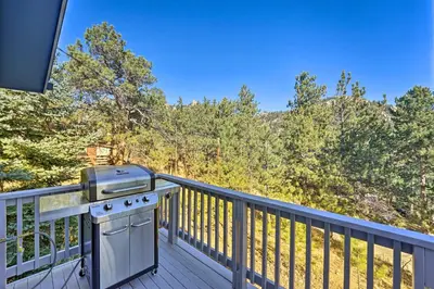 a grill on a deck with a view of trees at Luxe Updated Home with Grill and Hot Tub 4 Mi to RMNP in Estes Park
