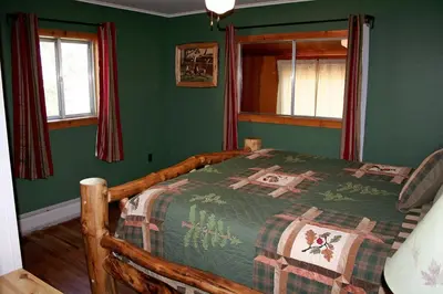 a bedroom with a wooden bed in a room with green walls at Mountain Pine Cabin by Rocky Mountain Resorts- #20NCD0296 in Estes Park