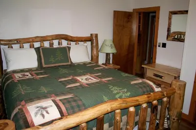 a bedroom with a wooden bed with a green blanket at Mountain Pine Cabin by Rocky Mountain Resorts- #20NCD0296 in Estes Park