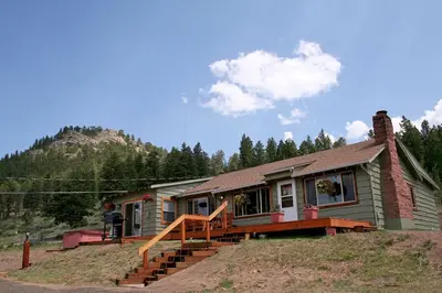 a house with a porch and a person standing in front of it at Rocky Mountain Retreat 2 by Rocky Mountain Resorts in Estes Park