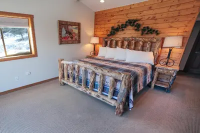 a bedroom with a bed with a wooden wall at Rocky Mountain Retreat 2 by Rocky Mountain Resorts in Estes Park