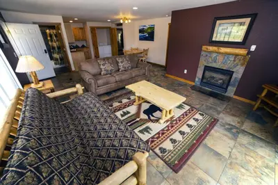 a living room with a couch and a table and a fireplace at Rocky Mountain Retreat 1A by Rocky Mountain Resorts in Estes Park