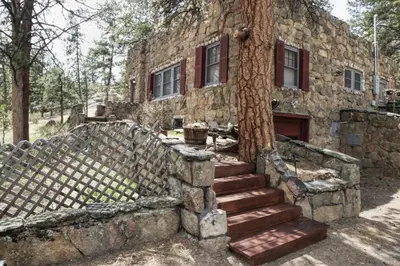 an old stone building with stairs next to a tree at Stonehaven Home by Rocky Mountain Resorts- #3384 in Estes Park