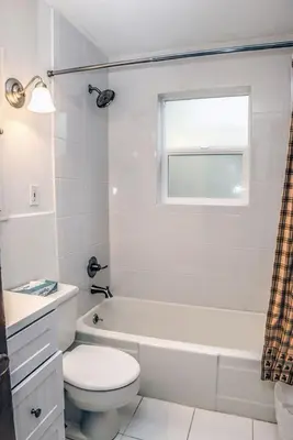 a white bathroom with a toilet and a tub and a window at Stonehaven Home by Rocky Mountain Resorts- #3384 in Estes Park