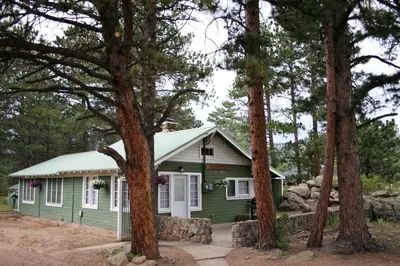 a green house in the middle of trees at Monte Verde by Rocky Mountain Resorts- #20NCD0297 in Estes Park