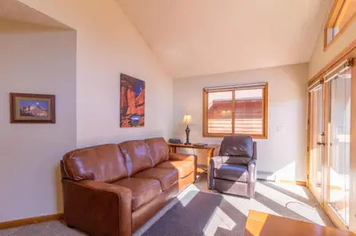 a living room with a leather couch and a chair at Woodlands on Fall River in Estes Park
