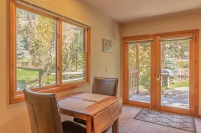 a dining room with a table and chairs and windows at Woodlands on Fall River in Estes Park