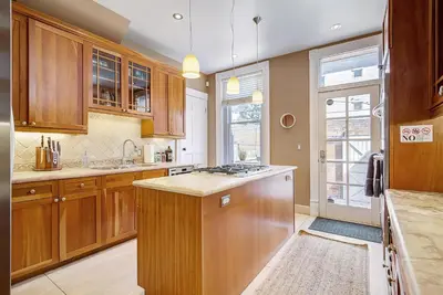 a kitchen with wooden cabinets and a stove top oven at Stunning Historic Home - DT Location! - Sleeps 8 in Denver