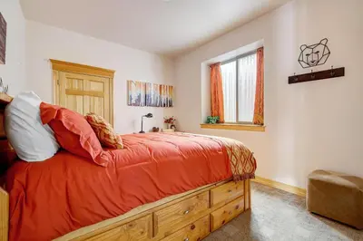 a bedroom with a bed with an orange comforter and a window at Secluded & Spacious Mountain Getaway in Morrison
