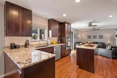 a kitchen with wooden cabinets and granite counter tops at Relaxing Escape + Large Deck - 12 Min to Red Rocks in Lakewood