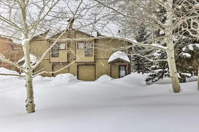 a house covered in snow with trees in the foreground at 10 Mi to Breckenridge Townhome with Hot Tub and Deck! in Frisco