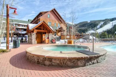 a hot tub in a patio with a building and a house at Premier 2 Bedroom Mountain Condo In River Run Village With Expansive Mountain Views And Walking Distance To Ski Slopes in Keystone
