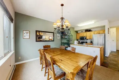 a dining room with a wooden table and a kitchen at Seasons 3 Bedroom Townhome At Lakeside Village in Keystone