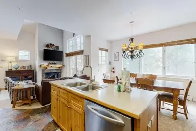 a kitchen and living room with a sink and a table at Seasons 3 Bedroom Townhome At Lakeside Village in Keystone