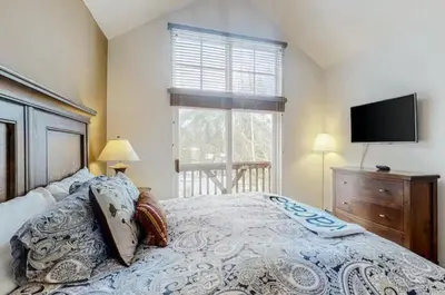 a bedroom with a bed with a tv and a window at Seasons 3 Bedroom Townhome At Lakeside Village in Keystone