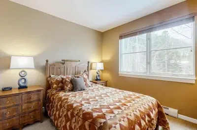 a bedroom with a large bed and a window at Seasons 3 Bedroom Townhome At Lakeside Village in Keystone