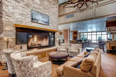 a large living room with a fireplace and a large stone wall at Seasons 3 Bedroom Townhome At Lakeside Village in Keystone