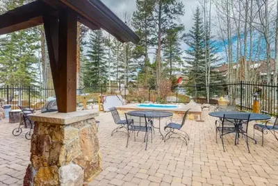 a patio with tables and chairs and a stone fireplace at Seasons 3 Bedroom Townhome At Lakeside Village in Keystone