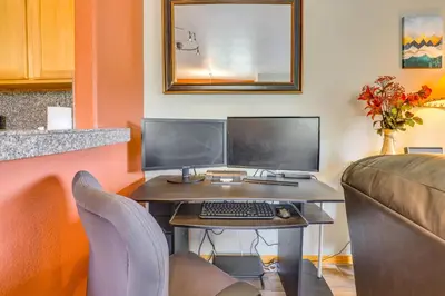 a desk with two computer monitors and a keyboard at Cozy Condo with Views, 3 Mi to Winter Park Resort! in Winter Park